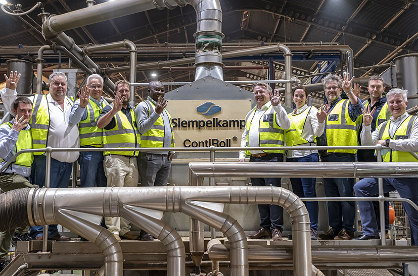 Siempelkamp-Mitarbeiter stehen auf einer Maschine und freuen sich