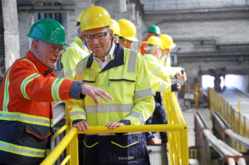 Uwe Reinecke, Werksdirektor von Feralpi Stahl, erläutert Energieminister Wolfram Günther das Drahtwerk