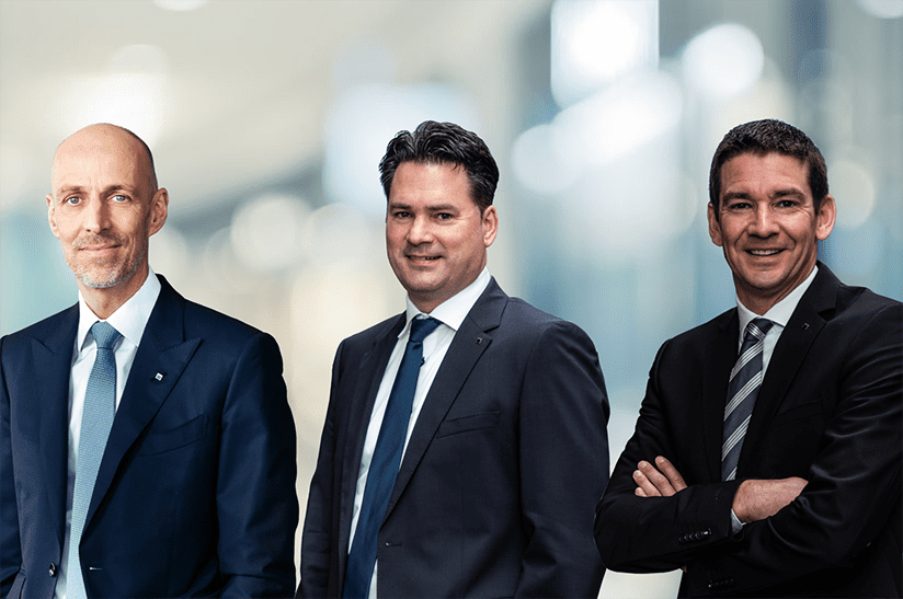 Das Bild zeigt drei weiße Männer, die um die 50 Jahre alt sind und dunkle Anzüge tragen. Sie gehören alle zum Technologieunternehmen Trumpf.