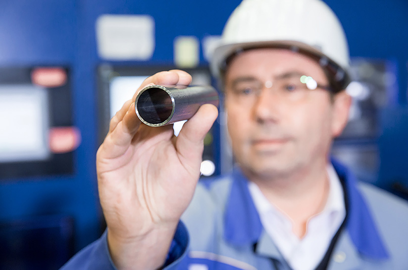 Das Bild zeigt unscharf einen gewerblichen Mitarbeiter von Benteler Steel/Tube, der in ein Stahlrohr schaut.