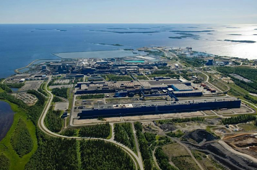 Das Bild zeigt das Werk von Outokumpu im finnischen Tornio aus der Adlerperspektive. Im Vordergrund ist etwas grüne Landschaft zu sehen, dann kommen die Anlagen und im Bildteil die See.