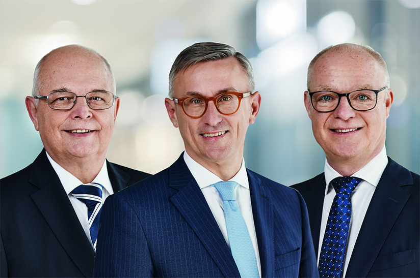 Das Bild zeigt die Porträts drei weißer Männer im Anzug. Sie tragen jeweils eine Brille und eine Krawatte. Es handelt sich dabei um die drei Vorstandsmitglieder von Voestalpine, deren Verträge Ende März 2024 auslaufen.