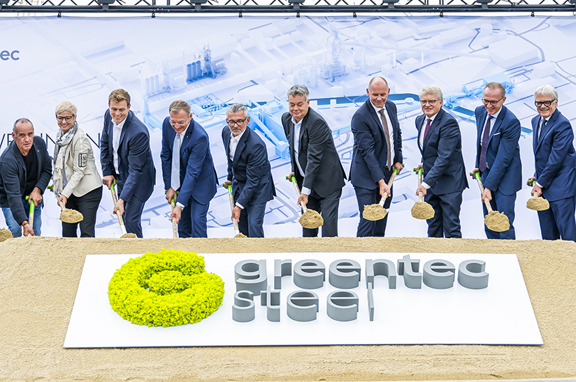Das Bild zeigt eine Reihe männlicher Führungskräfte, darunter eine Frau, die den symbolischen ersten Spatenstich für einen Neubau bei Voestalpine in Linz setzen.