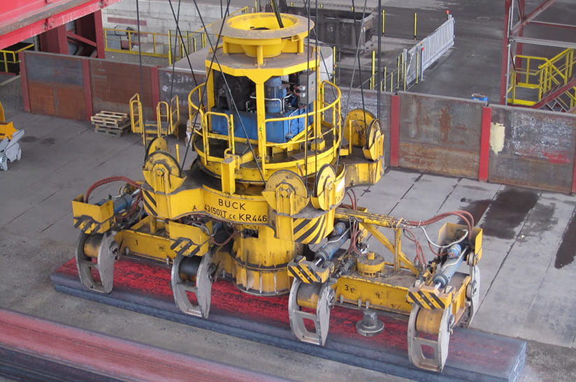 Das Bild zeigt einen Zangenkran, der eine glühende Bramme ablegt. Dabei kommt Technik von Symeo zum Einsatz.