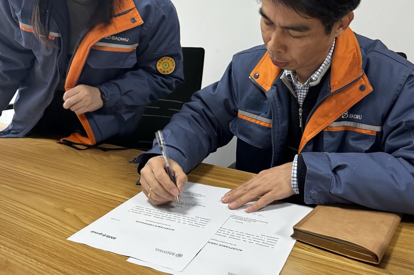 Auf dem Foto sind Zhuang Hua und Li Jiancheng von Baosteel Engineering and Technology Ltd. bei der Unterzeichnung der Endabnahmebescheinigung im Büro von Baosteel Engineering zu sehen.