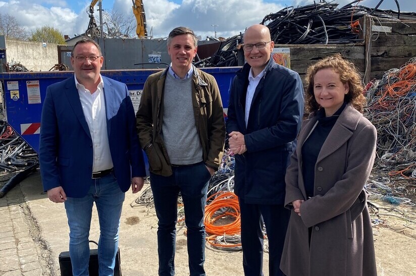 Vier Personen vor Stahlschrott: Experten diskutieren über Fachzeitschriften.