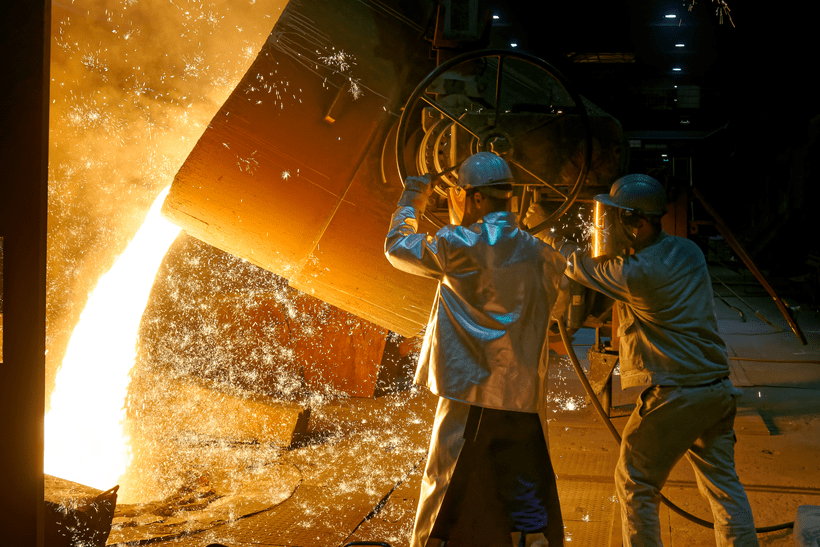 Stahlarbeiter beim Gießen von flüssigem Metall in einem Stahlwerk.