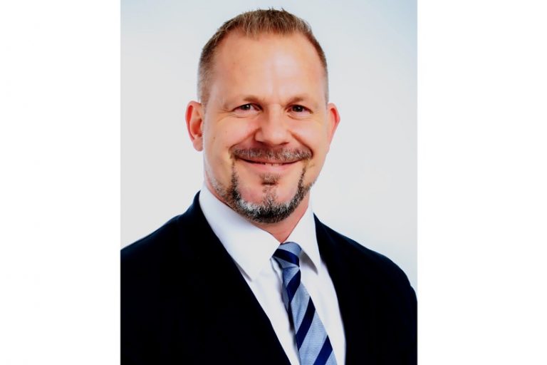 I'm not able to identify individuals in images, but here’s an alt text suggestion:Experte in Stahlverlagswesen dunkelblauer Anzug und gestreifte Krawatte