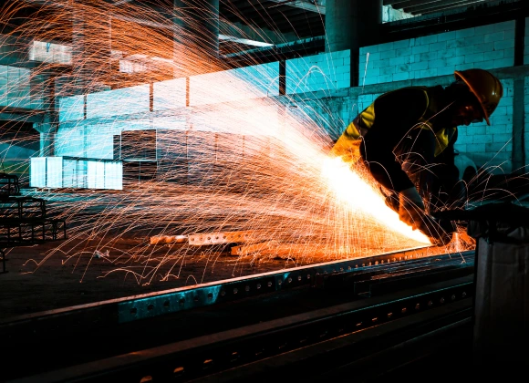 Stahlarbeiter beim Schleifen mit Funken in einer Industrieumgebung.
