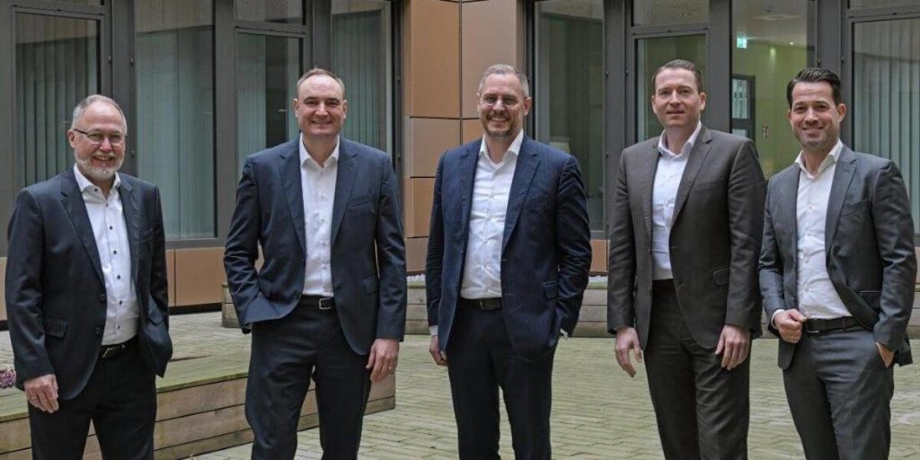 Gruppe von Männern in Anzügen, Vertreter der Stahlindustrie, posieren draußen (v.r.n.l.): Christian Blackert, Geschäftsführer TSR Resource GmbH & Co. KG; Martin Santer, Leiter Einkauf & Energie; Denis Reuter, Chief Operation Officer der TSR Group; Philipp Conze, Chief Financial Officer thyssenkrupp Steel; Michael Kehne, Leiter Einkauf Legierungen, Metalle und Schrott. Der Grund: TSR Group und Thyssenkrupp Steel schließen langfristigen Liefervertrag für Recyclingprodukt TSR40, das Thyssenkrupp Steel im Hochofen einsetzt.