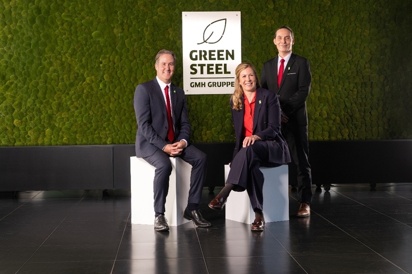 Team der Green Steel GMH Gruppe vor Logo, spezialisiert auf Stahlpublikationen.