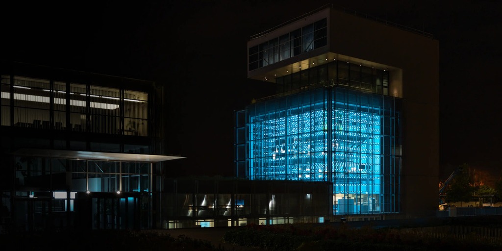 Die voestalpine Stahlwelt bei Nacht: Die gläserne Fassade macht den rund 140 Tonnen schweren „Grid“ sichtbar und verwandelt die Ausstellung in ein weithin leuchtendes Wahrzeichen des Werksgeländes
