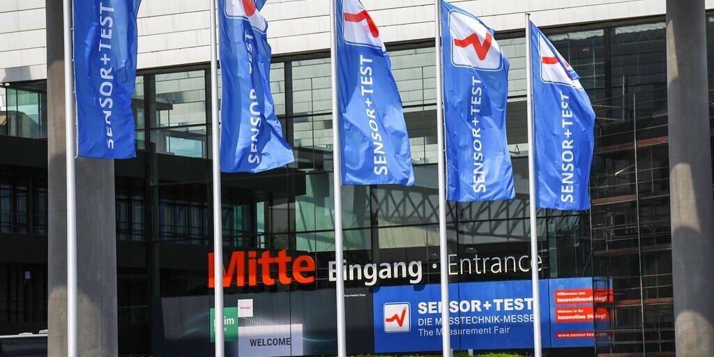 Die Sensor + Test 2026 findet in Nürnberg statt. Das Foto zeigt den Eingangsbereich der Messe mit Fahnen zur Veranstaltung.