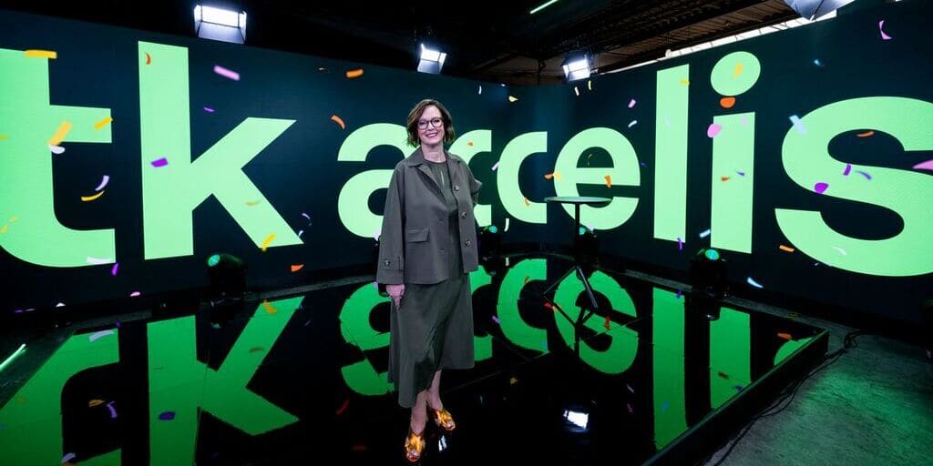 Ilse Henne, CEO von tk accelis, vor dem neuen Unternehmenslogo des Werkstoff- und Lieferkettendienstleisters.