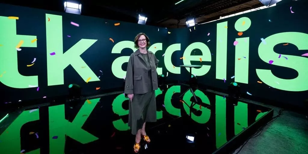 Ilse Henne, CEO von tk accelis, vor dem neuen Unternehmenslogo des Werkstoff- und Lieferkettendienstleisters.