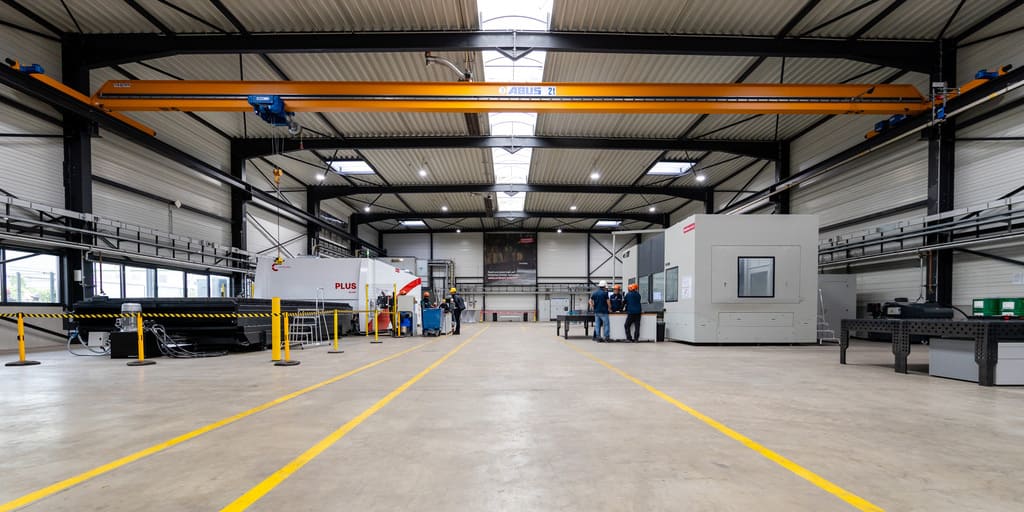 Fertigungshalle von Ambo Stahl – im Hintergrund Menschen und Maschinen