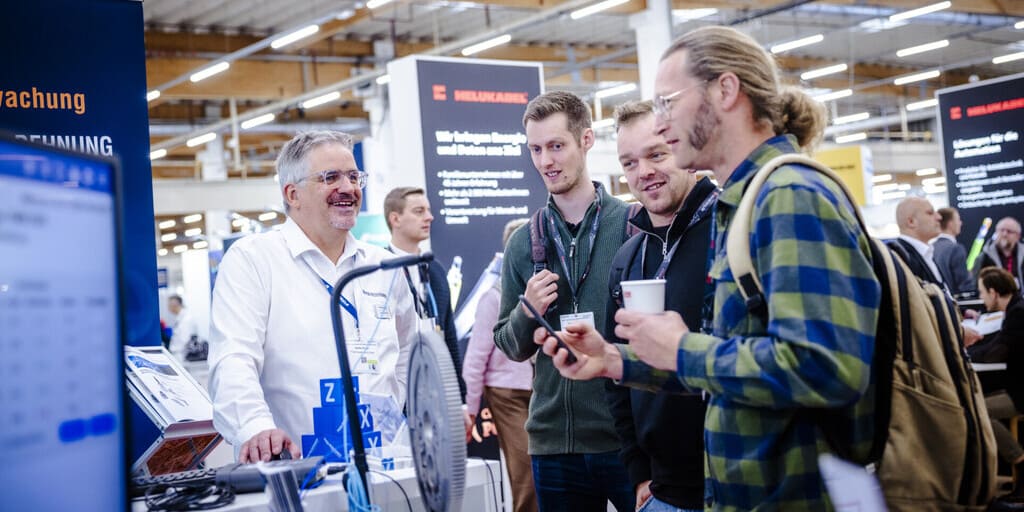 Fachbesucher im Gespräch an einem Messestand – die FMB 2026 findet im November in Bad Salzuflen statt.