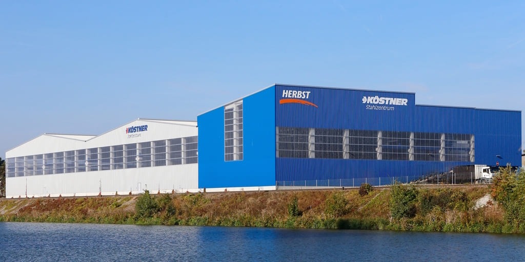 Außenansicht von Köstner Stahlzentrum in Bamberg mit blau-weißen Lagerhallen am Wasser
